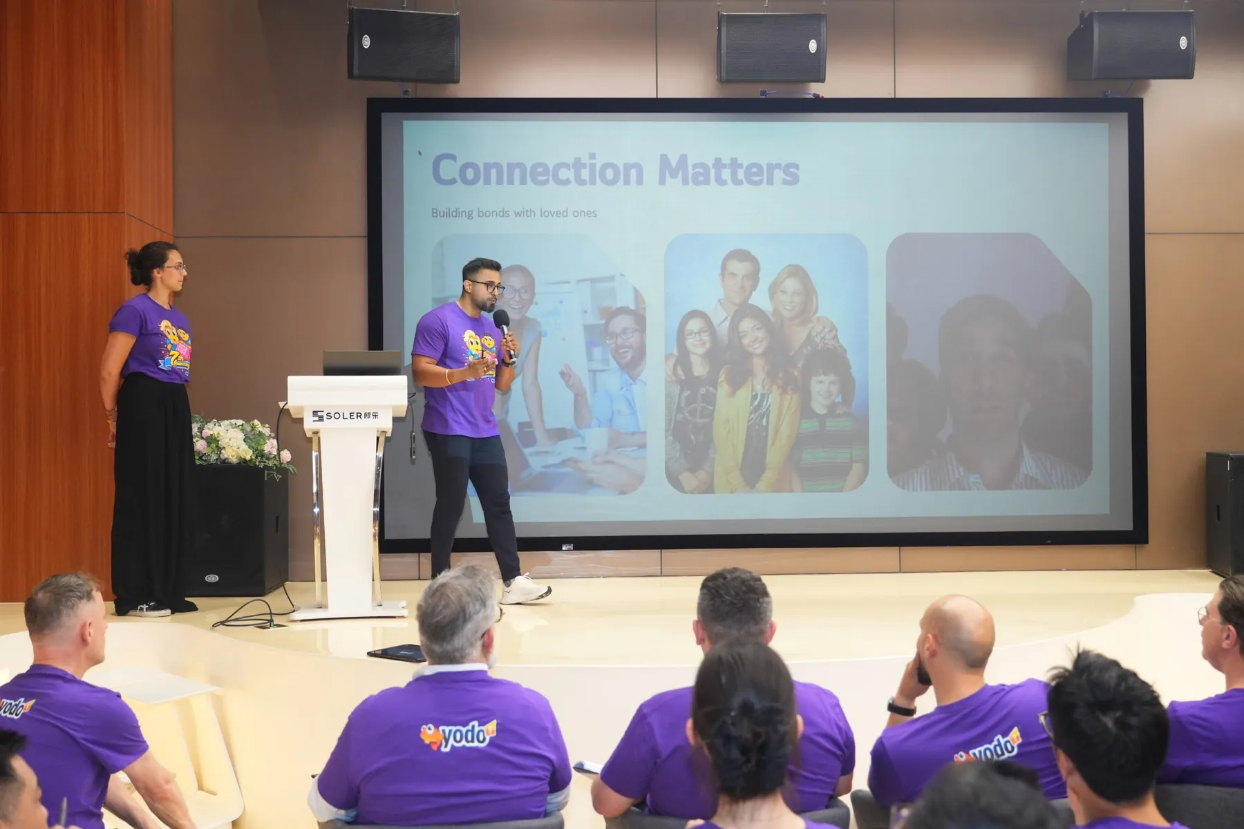 Dhee presenting a slide titled Connection Matters to a seated audience.